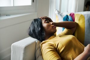 mulher sentindo tontura deitada no sofá. labirintite.